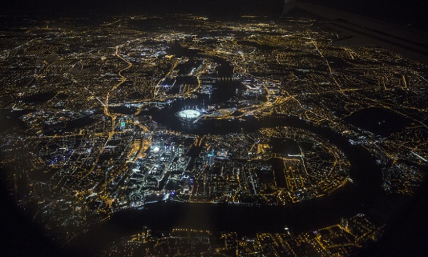 All lit up, the black outline of the River Thames snakes its way through the city of London passing by Canary Wharf and the illuminated O2 Dome.