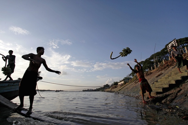 Men unload bananas from a boat on the Rangoon river, Burma.