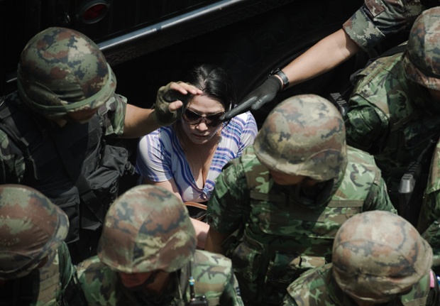 A woman who was part of the movement to topple the government is taken to safety by Thai soldiers as anti-coup protesters started to attack her in Bangkok.