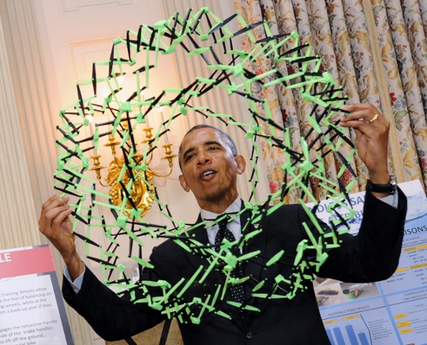 President Barack Obama holds a Model used to show how polymers expand as he learns how sandless sandbags work that are the invention of Peyton Robertson, 12, of Ft. Lauderdale, Fla.,  while touring the 2014 White House Science Fair exhibits on display in the State Dining Room of the White House in Washington.