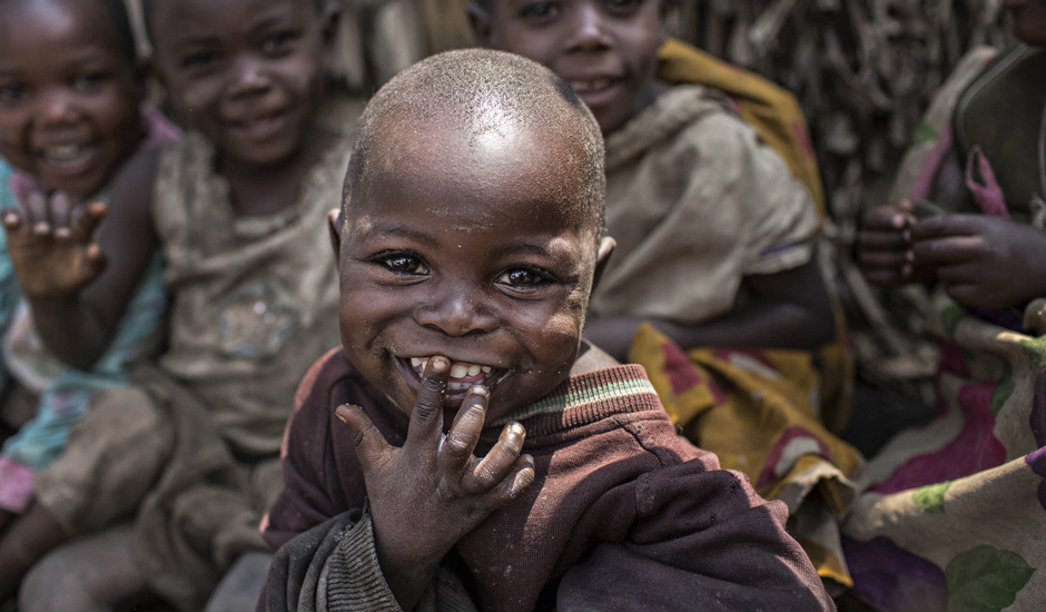 An internally displaced child smiles at the camera during a distribution of tarps in Mubimbi