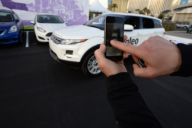 A Valeo representative swipes his finger across an iPhone to initiate a self parking demonstration at the 2014 International CES in Las Vegas, Nevada, January 8, 2014. The car, a Range Rover Evoque with Valeo self-parking technology, is equipped with 12 ultrasonic sensors, six in back and six in front, a laser scanner mounted in the grille, and four cameras.