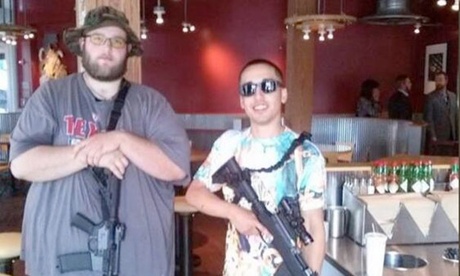 Two men post in an empty Chipotle restaurant in Dallas with assault rifles slung round their necks