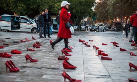 A woman walks past hundreds of red shoes in Palermo, to raise awareness at the violence against women.