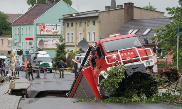 A fire engine is half sunken in a road that collapsed after heavy overnight rainstorms in Glucholazy, Poland. The sinkhole opened up following storms and severe flooding in the region.