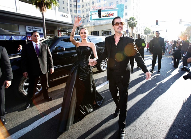 Angelina Jolie waves to fans as she arrives with actor Brad Pitt for the premiere of 'Maleficent' in Hollywood. A celebrity prankster was arrested for punching Brad Pitt on the red carpet.