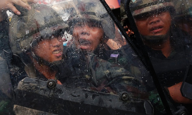 Soldiers protect themselves with shields during a confrontation with anti-coup protesters in Bangkok , Thailand.