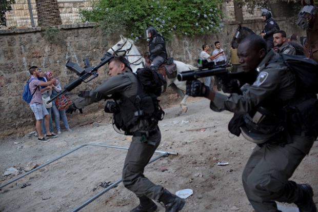 Street drama: Israeli police officers shoot a stun grenade towards Palestinians and mounted officers detain small groups in Jerusalem as the city commemorates Israel taking control of the Old City during the Six Day War in 1967. 