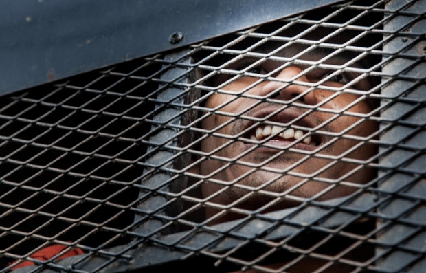 One of the 23 people arrested last January after violent clashes between protestors and security forces smiles from the prison van as he arrives early morning at the Phnom Penh Municipal Court of First Instance ahead of his verdict in Phnom Penh, Cambodia.