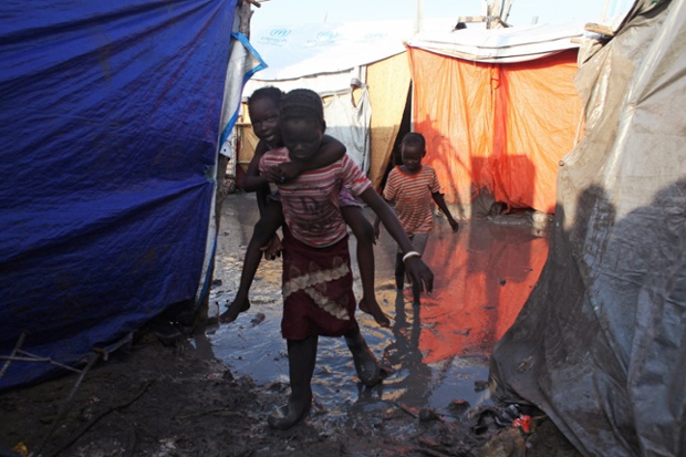 A South Sudanese girl displaced by the conflict carries a younger boy on her back as they walk through mud in a flooded camp for internally displaced people at the UNMISS base in Malakal, Upper Nile State.