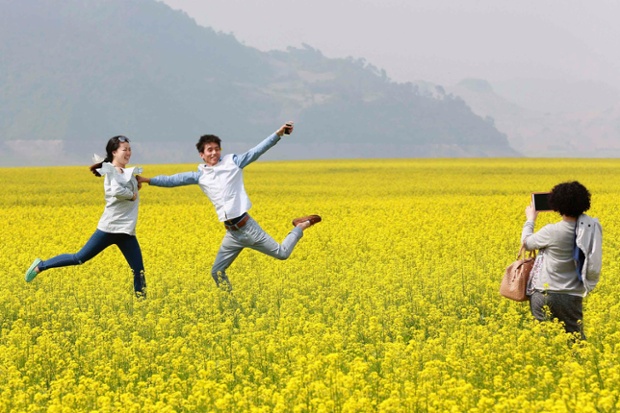 Visitors pose for pictures at a canola flower field in Kuandian county, near China's border with North Korea, Liaoning province.