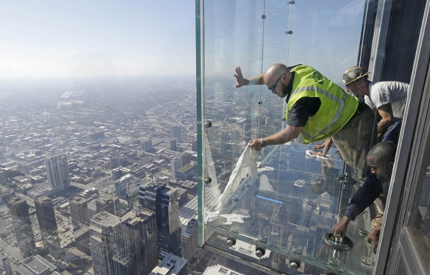 Glaziers from MTH Industries finish replacing a layer of protective coating over the glass surface on the floor of one of four transparent ledges that jut out from the 103rd floor of the Willis Tower in Chicago. The see-through glass bays known as The Ledge were designed with a protective coating that completely covers all glass surfaces to protect against scratches.