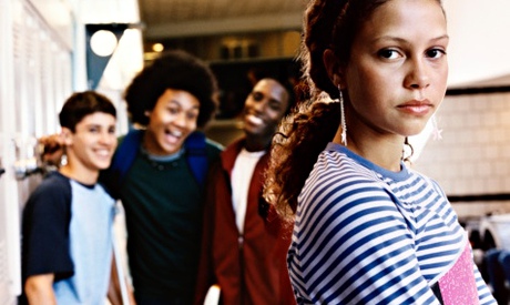 Serious Female Student Looking at the Camera, with Three Boys Standing in the Background Laughing at