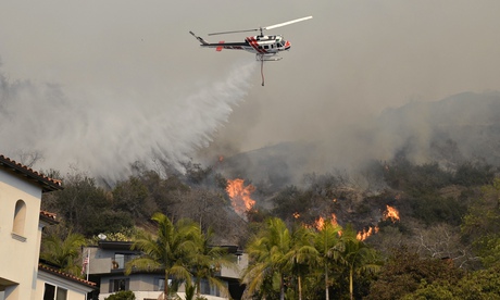 A helicopter drops water on a wildfire in California