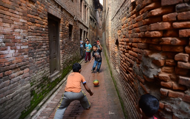 Undeterred by the narrow play area, Nepalese children play football in a passageway in Bhaktapur, near Kathmandu. 