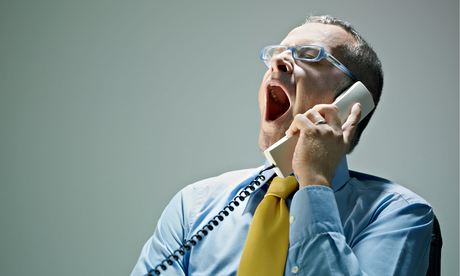 Caucasian businessman yawning and talking on telephone