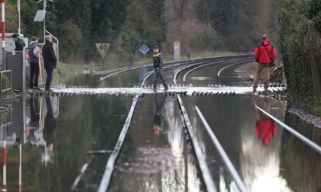 Locals cross flooded railway lines after the river Thames burst its banks in Datchet.