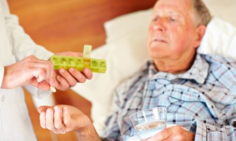 Old man in bed being given a pill by doctor
