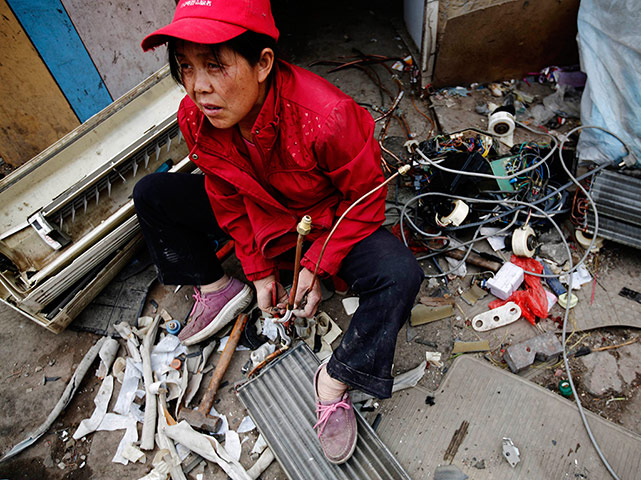 e-waste from the agencies: A woman dismantles a broken air-conditioning unit 