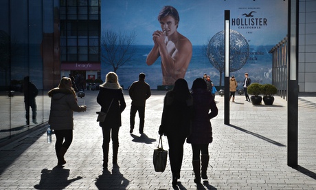 Chinese shoppers walk past a new Hollister clothing store in Beijing