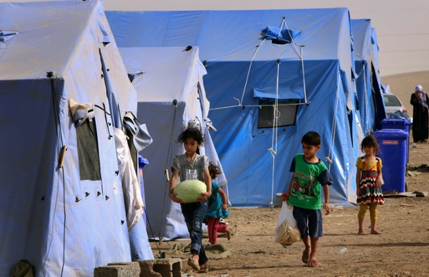 Children walk outside temporary tents set up to shelter Iraqis fleeing violence in Iraq's northern Nineveh province in Aski Kalak, 40 kms West of Arbil, in the autonomous Kurdistan region.