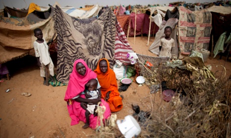 Women and their children sit outside their tents at the Zam Zam refugee camp for internally displaced people in North Darfur, Sudan