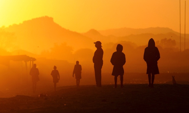 A Marikana resident watches the sunrise as students walk to school on South Africa's Platinum Belt