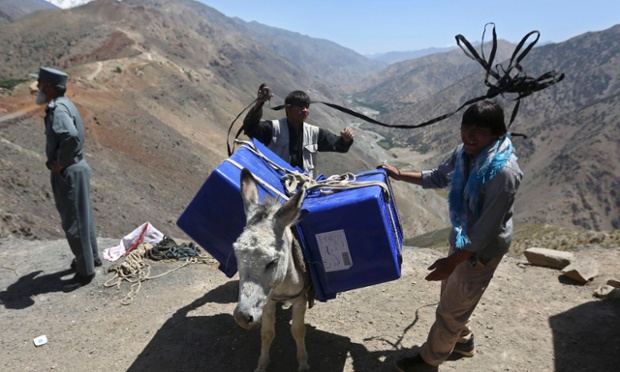 Afghan men lead a donkey, loaded with ballot boxes and other election material to be transported to polling stations which are not accessible by road, in Shutul, Panjshir province