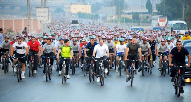 Egypt's President Abdel Fattah al-Sisi (centre in white) rides a bicycle with few hundred cyclists as he called on people to cycle and walk more in order to save money for the country.