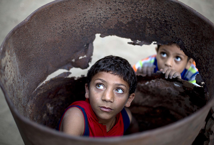 20 Photos: Palestinian boys play in a barrel outside their home in Beit Lahia
