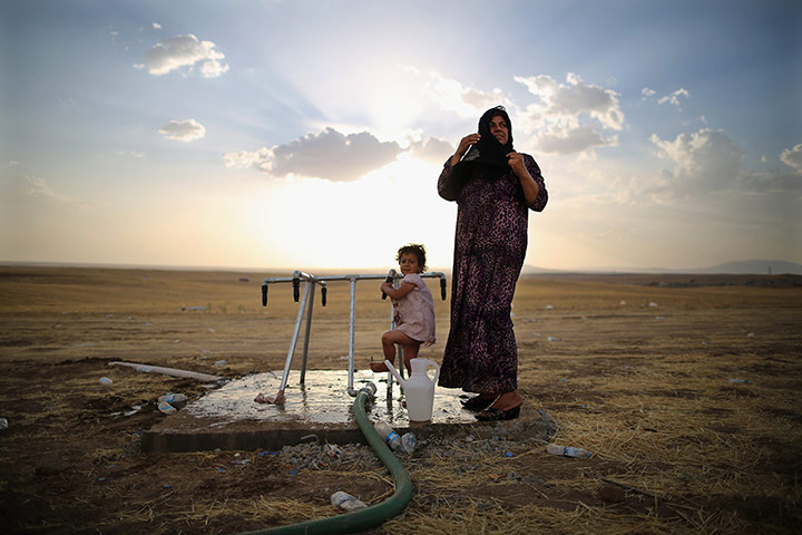 20 Photos: a women and a girl at a camp set up next to a Kurdish checkpoint