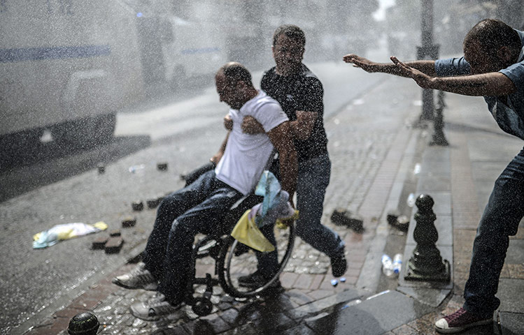 20 Photos: People help a man in a wheelchair during a clashes in Istanbul