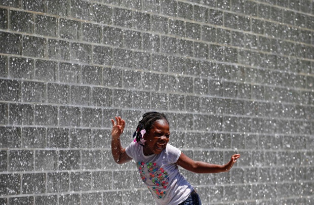 A girl dances under the waterfall from Crown Fountain in Chicago, Illinois.