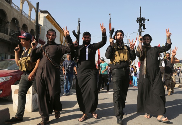 Shiite tribal fighters raise their weapons and chant slogans against the al-Qaida-inspired Islamic State of Iraq and the Levant (ISIS) in the northwest Baghdad's Shula neighborhood, Iraq.