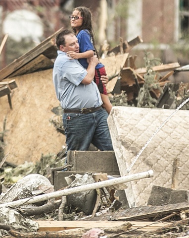 A man holds a girl after she was pulled from the basement of her destroyed home