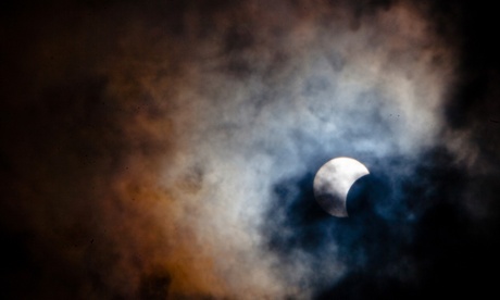 Rare hybrid solar eclipse with the moon obscuring the sun, seen through clouds from Tenerife.