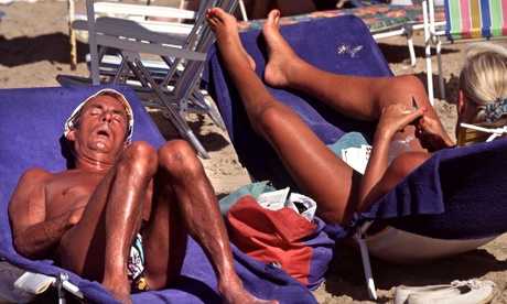 Snoozing sunbathers on loungers in Benidorm, Spain, with deep tans