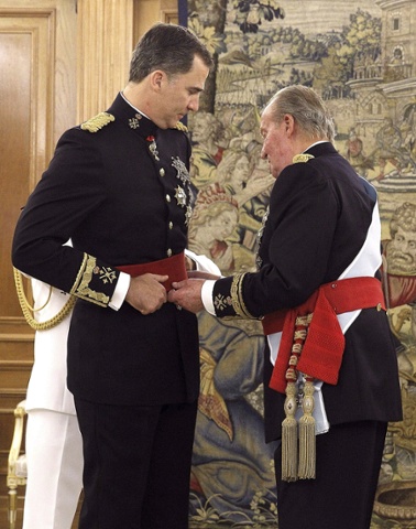 King Juan Carlos places the sash of the captain general of the armed forces on his son King Felipe VI of Spain in a ceremony held in the Hearing Room Zarzuela Palace