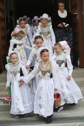 Girls in traditional Sorbian folk dress leave a church to take part in a procession