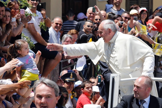 Pope Francis waves to a girl on his way to visit the John Paul I seminary in Cassano allo Jonio, southern Italy.