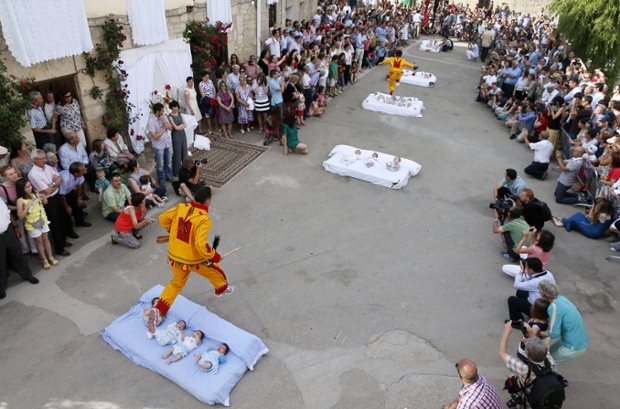 A man dressed up as the devil jumps over babies lying on a mattress in the street during El Colacho. Photograph: Cesar Manso / AFP / Getty Images