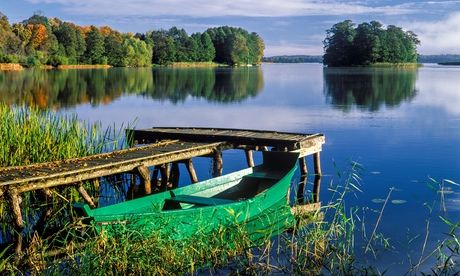 A wooden boat and wooden jetty on a still Masurian Lake in Poland