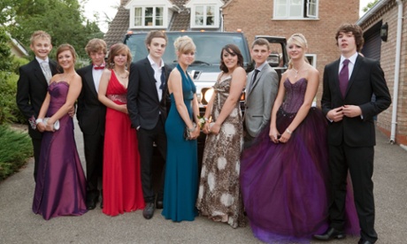 teenage girls and boys dressed up ready for their school prom pose in front of their limo