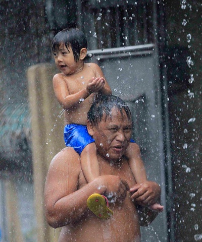 A sudden downpour soaks a father and son in Manila. It's the rainy season in the Philippines.