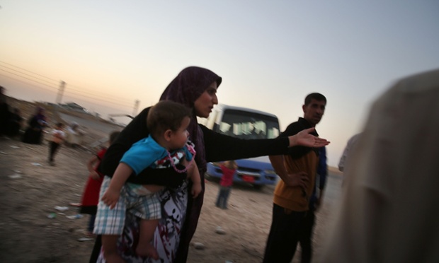 Families wait outside the camp.