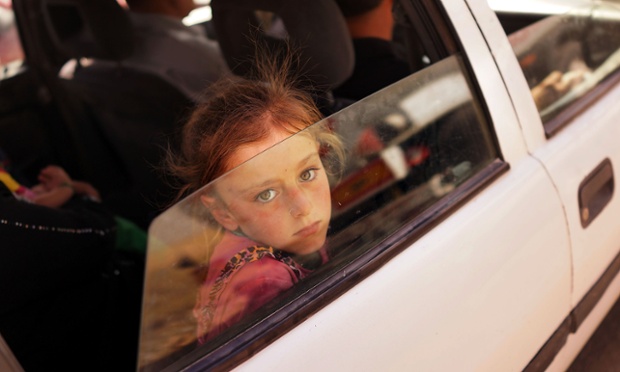 A child looks out of the window of her car as she waits to get into a the camp.