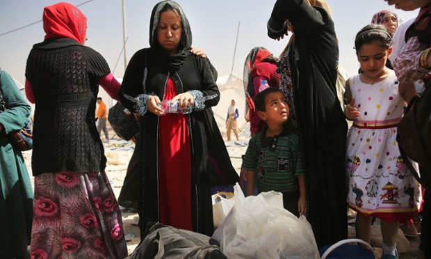 Women and children wait outside the camp.