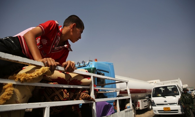 A boy sits on top of his family's belongings.