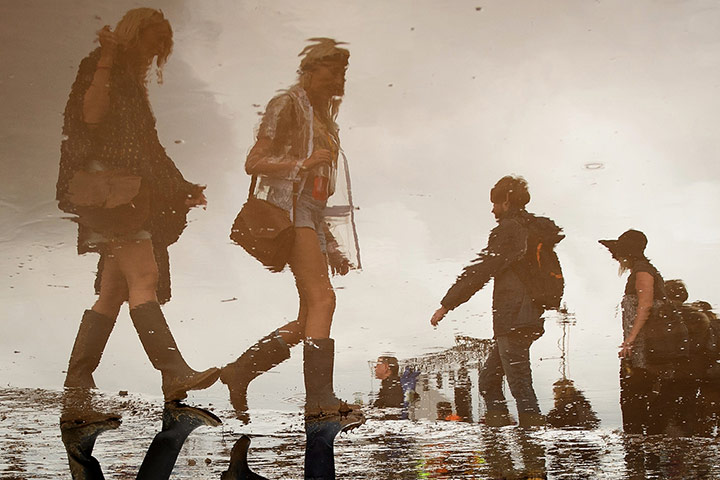 20 Photos: Revellers are reflected in a puddleat the Glastonbury Festival in Somerset