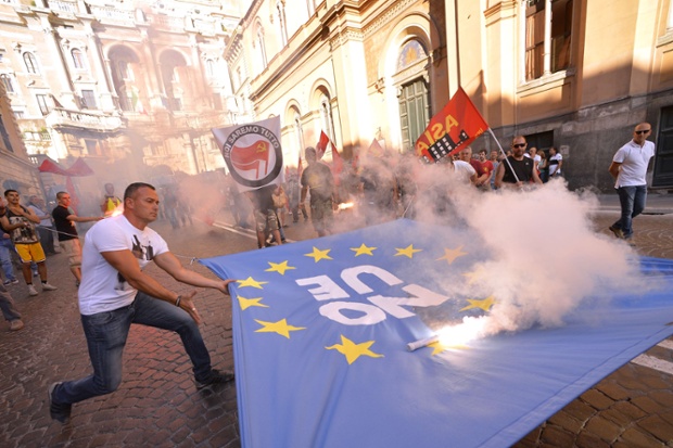 A plain clothes police officer snatches a flag reading No UE from protesters during a demonstration in Rome.
